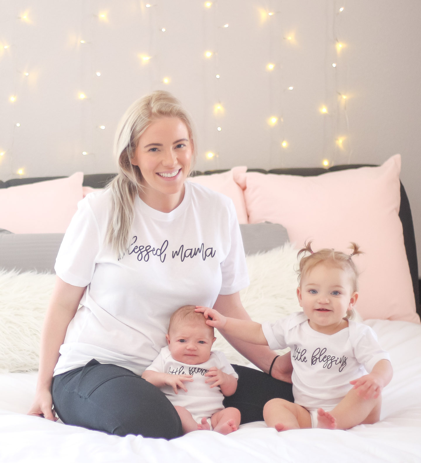 mom, toddler, and baby in matching mommy and me tees sitting on bed