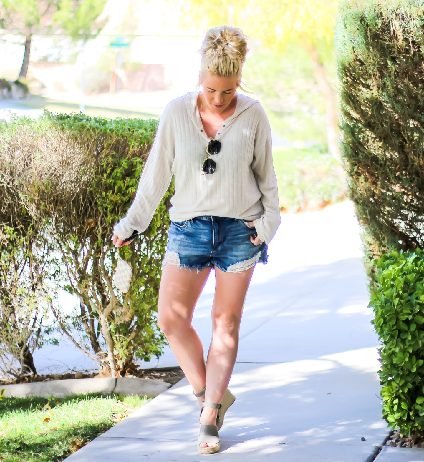woman style blogger standing outside wearing a cream plush hooded top, denim cutoffs, ,and espadrille wedges