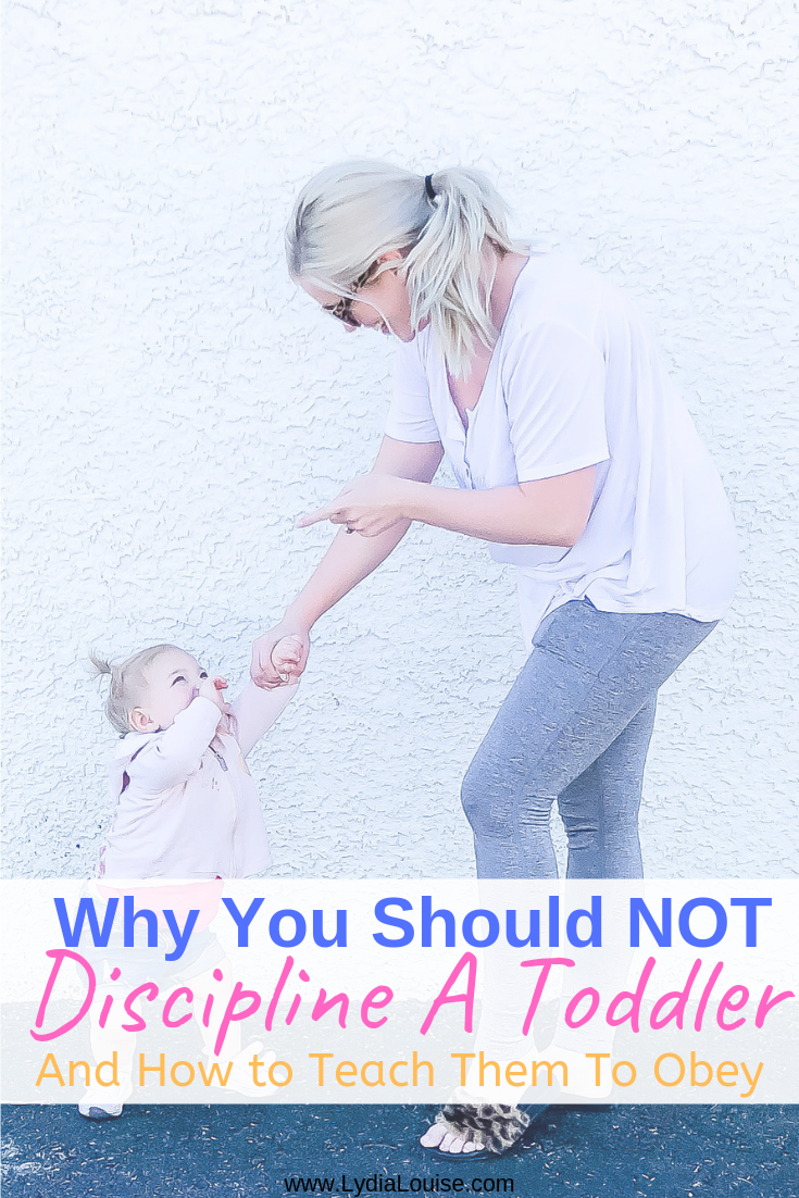 Mommy blogger standing with toddler daughter, holding hands and wagging her finger